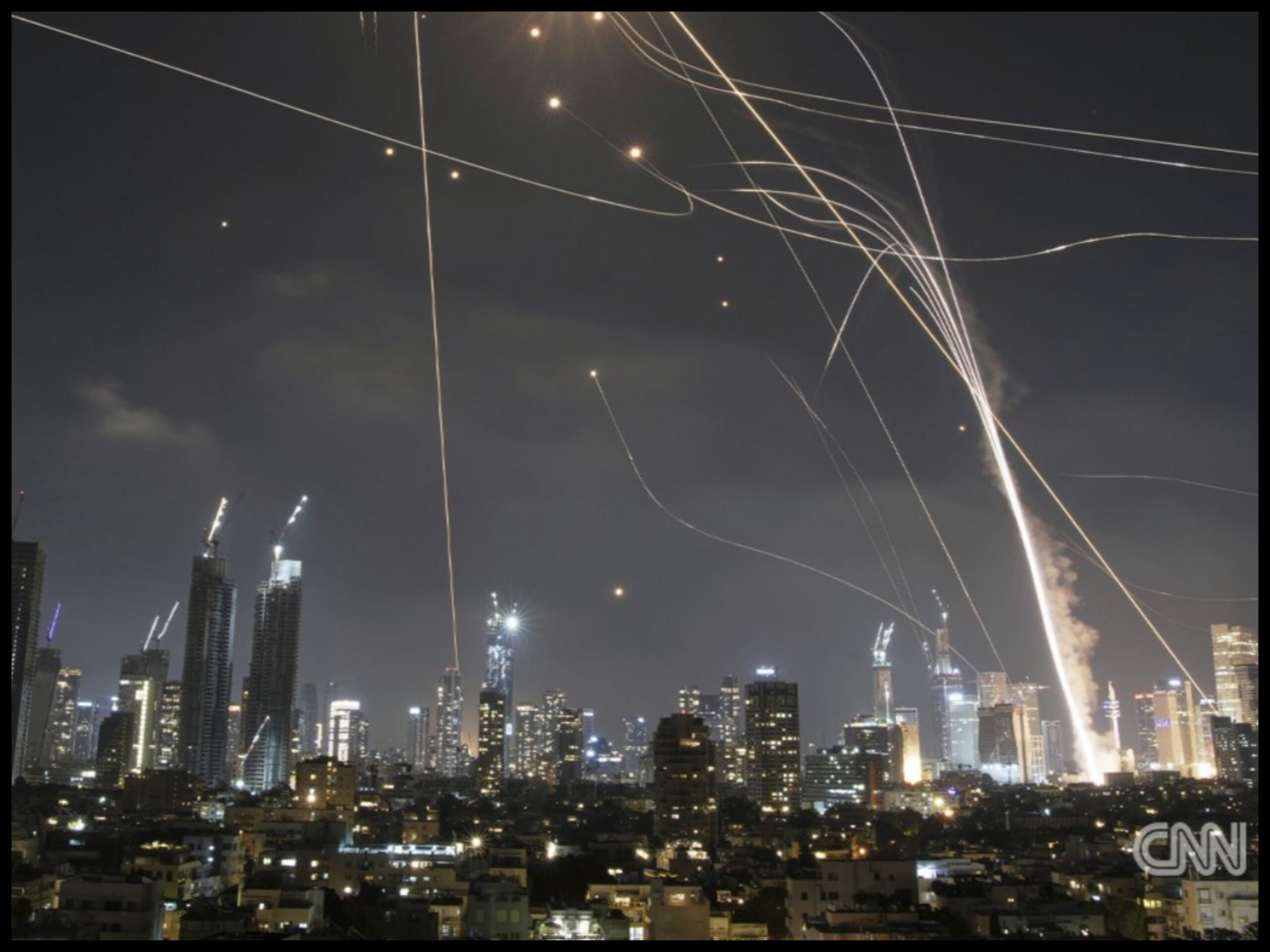 Iran attack Israel retaliation with missiles and drones lighting up the night sky over Tel Aviv during escalating military conflict.
