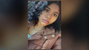 Yadira Hernandez-Castro smiling in her graduation gown and holding flowers