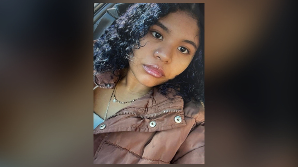 Yadira Hernandez-Castro smiling in her graduation gown and holding flowers