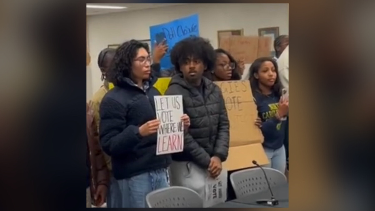 College students holding protest signs against the removal of campus early voting sites