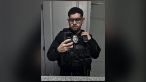 Man in tactical vest with police gear posing for a selfie, Asheville impersonation case